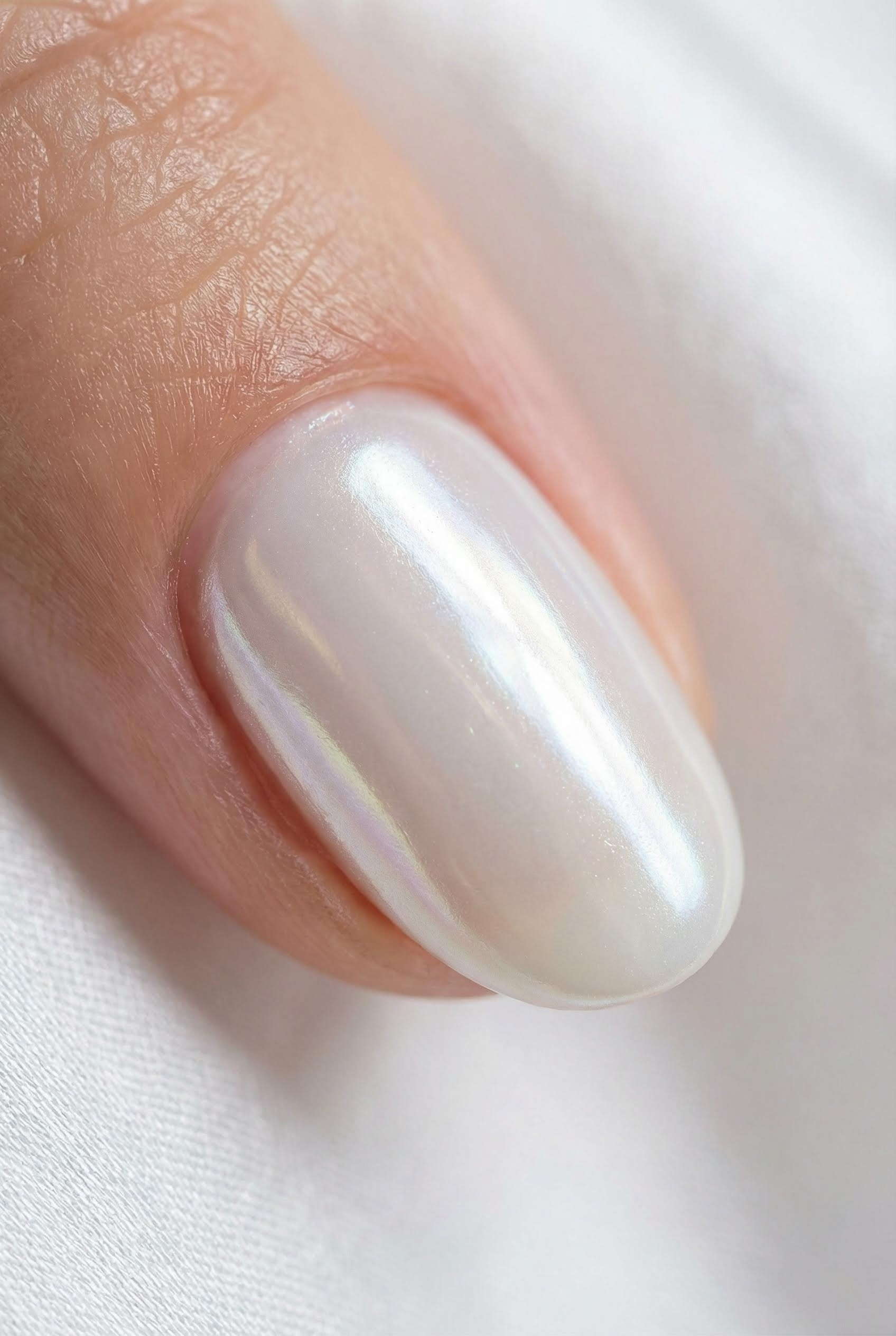 Extreme close-up macro shot of a fingernail showing the smooth, iridescent texture of chrome powder.