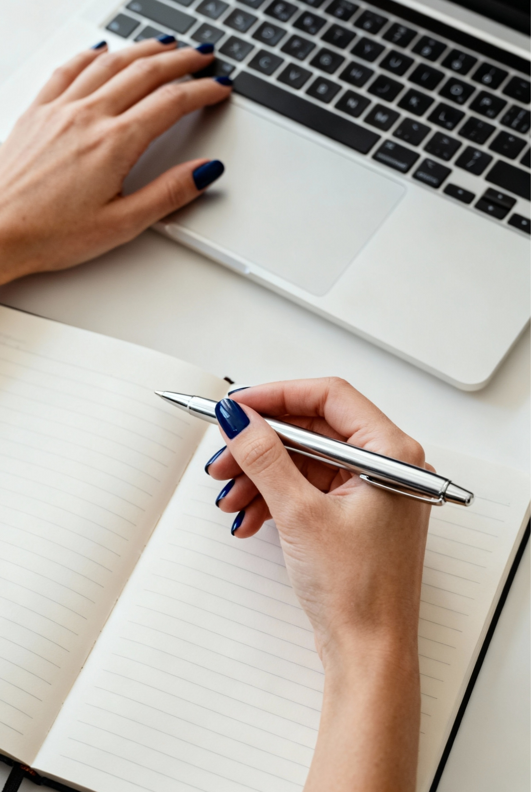 Sophisticated Depth: The Midnight Blue and Navy Nails Manicure 2 Woman's hand with short dark blue nails holding a pen over a notebook in a professional workspace.