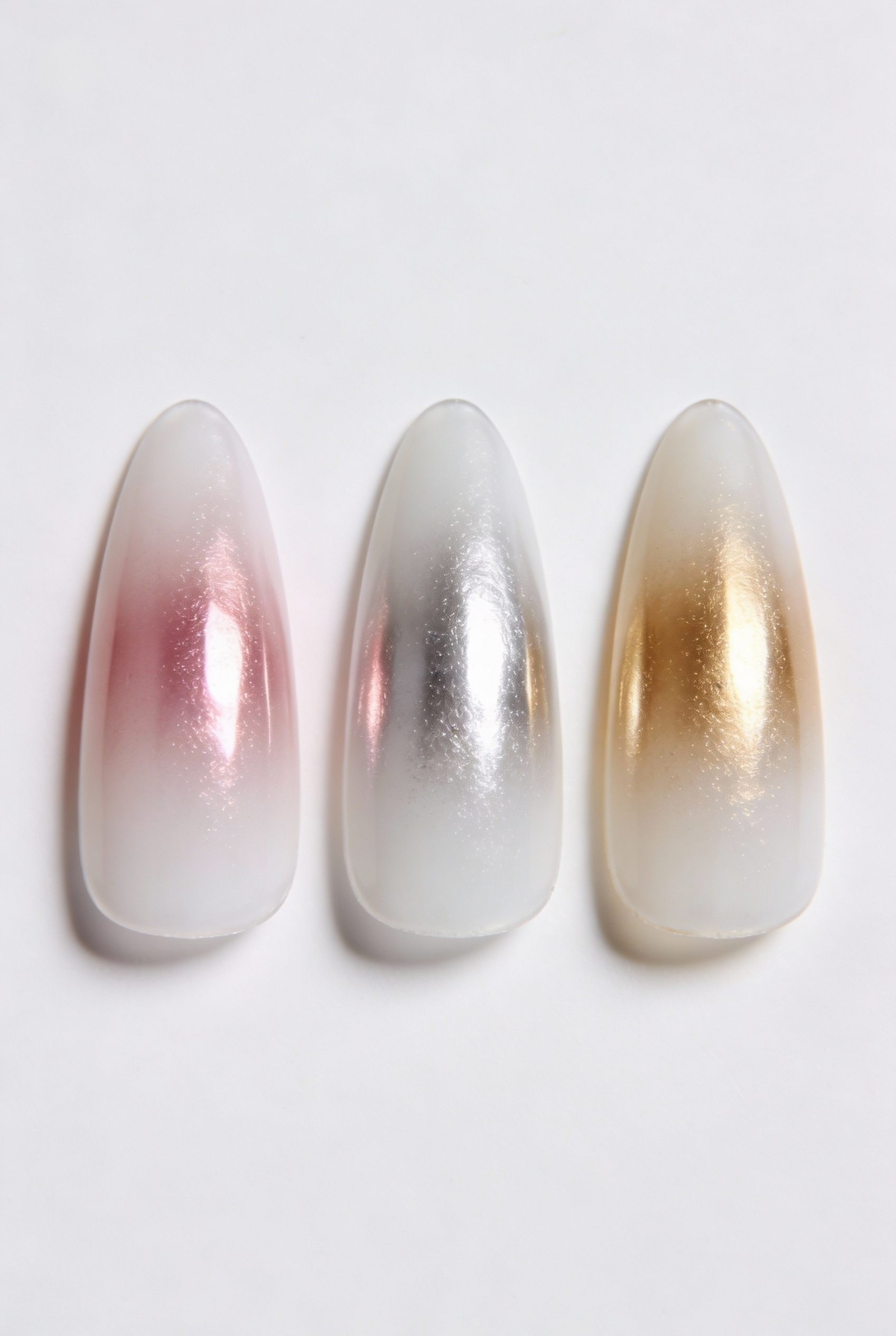 Three nail tips displaying different chrome powder shifts: pink, silver, and gold on a white base.
