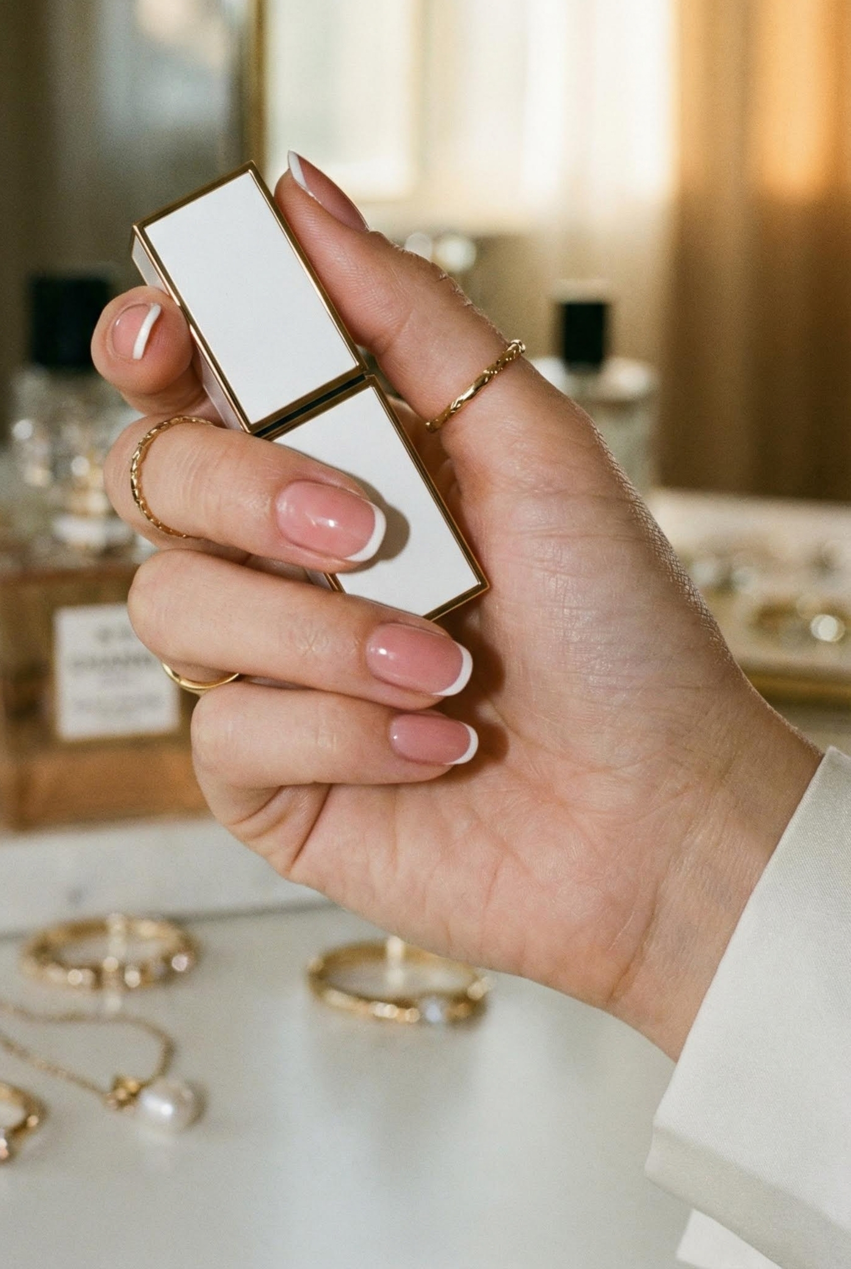 Minimalist Chic: The Ultimate Guide to the Modern Micro French Manicure 3 Hand holding a lipstick case highlighting the glossy sheer nude base color of a micro french manicure.
