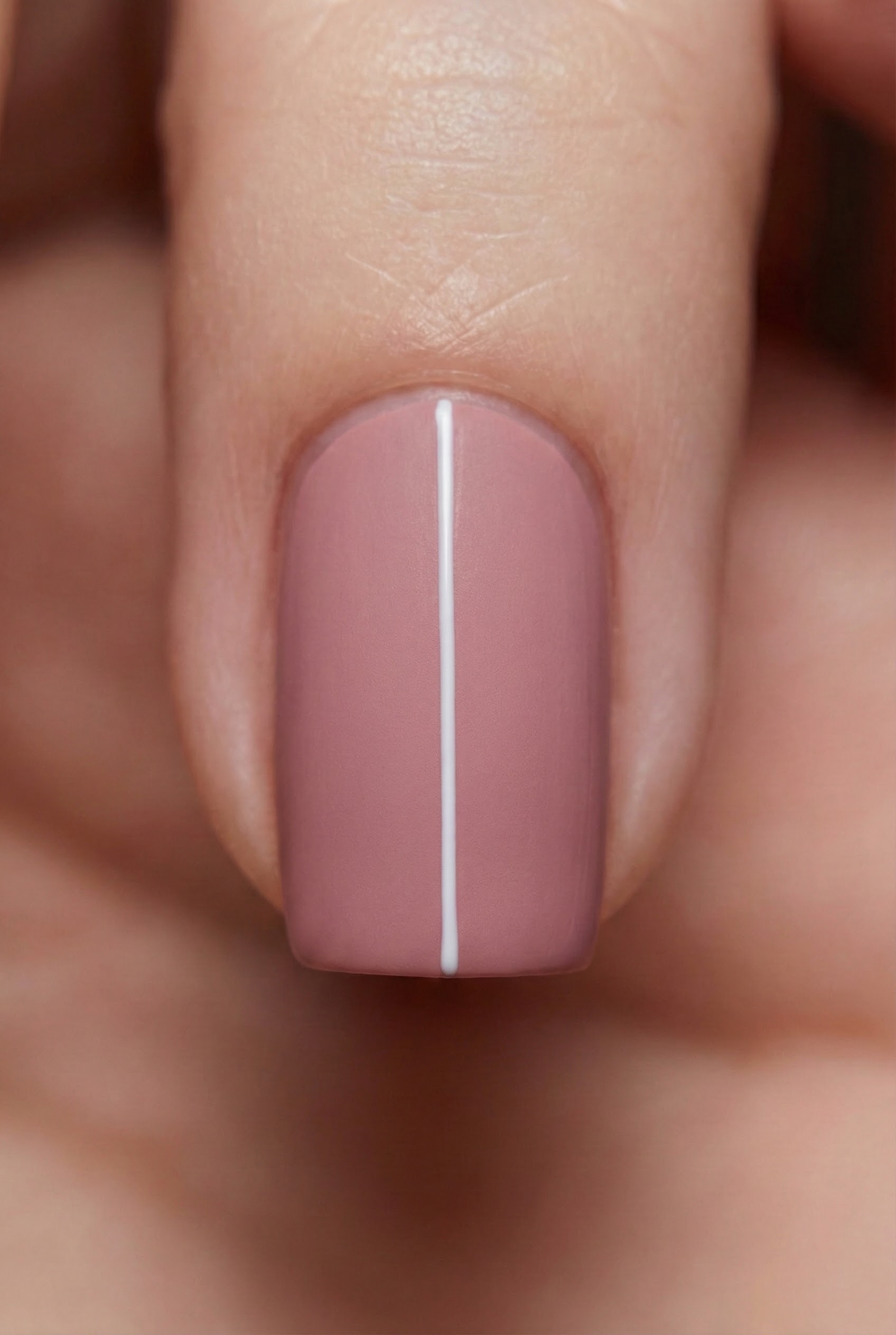 Macro photography of a dusty rose nail featuring a single, thin white vertical line down the center.