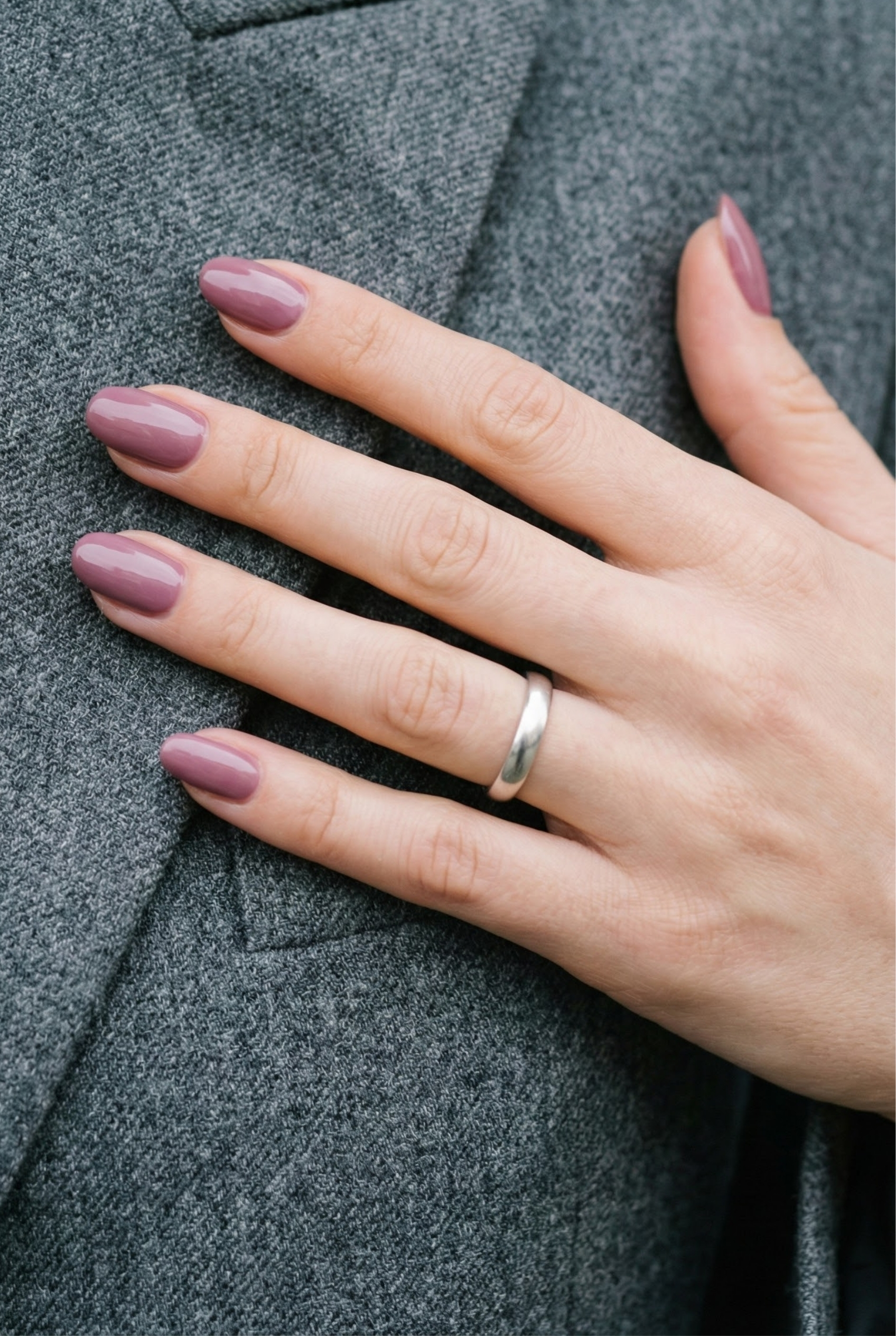 Glossy mauve nails styled with a grey wool blazer and a simple silver ring, showcasing professional fashion.