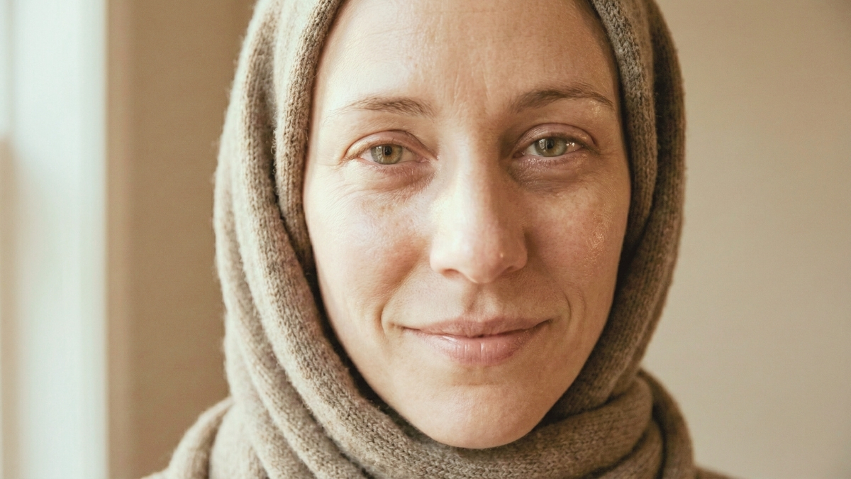 Natural portrait of a tired mother in soft daylight, showing subtle under-eye shadows and a calm, realistic expression