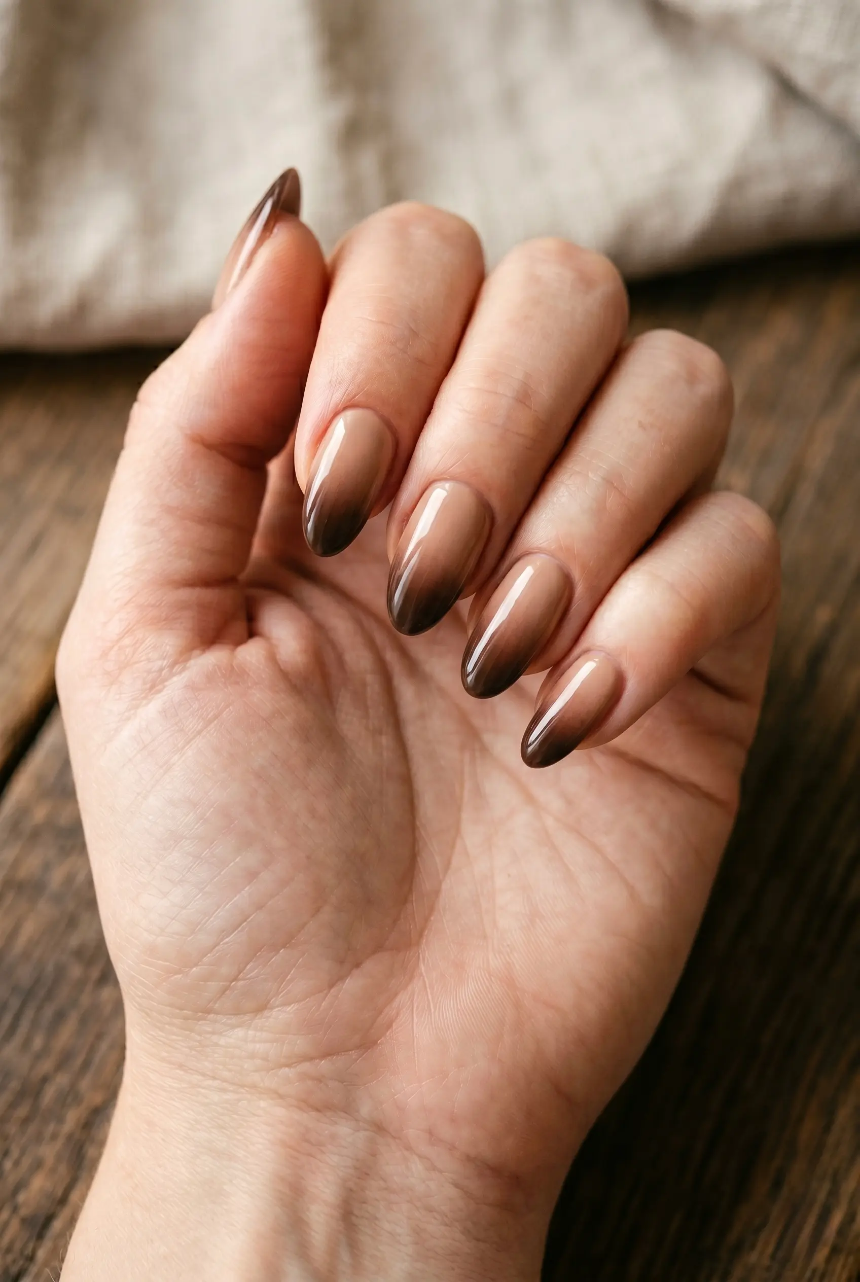 A top-down macro view of almond nails with a smooth gradient transition from soft latte brown to a deep espresso shade.