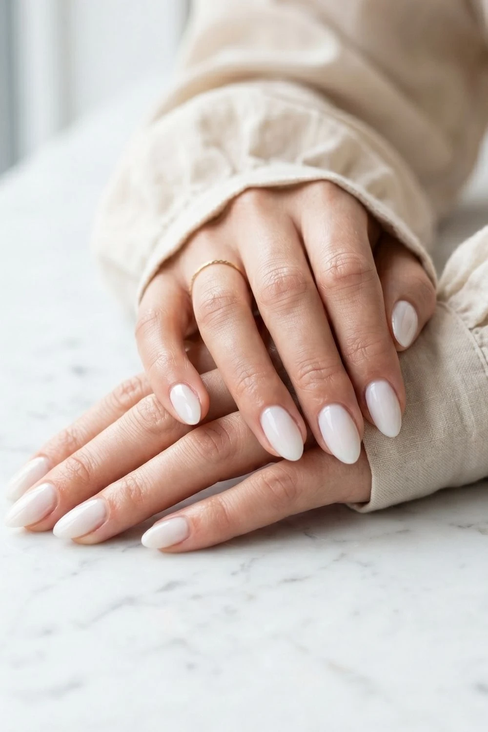 Why Women Are Filing Down Their Long Tips for This Nail Shape 1 Short almond-shaped nails with blush-toned polish on marble surface