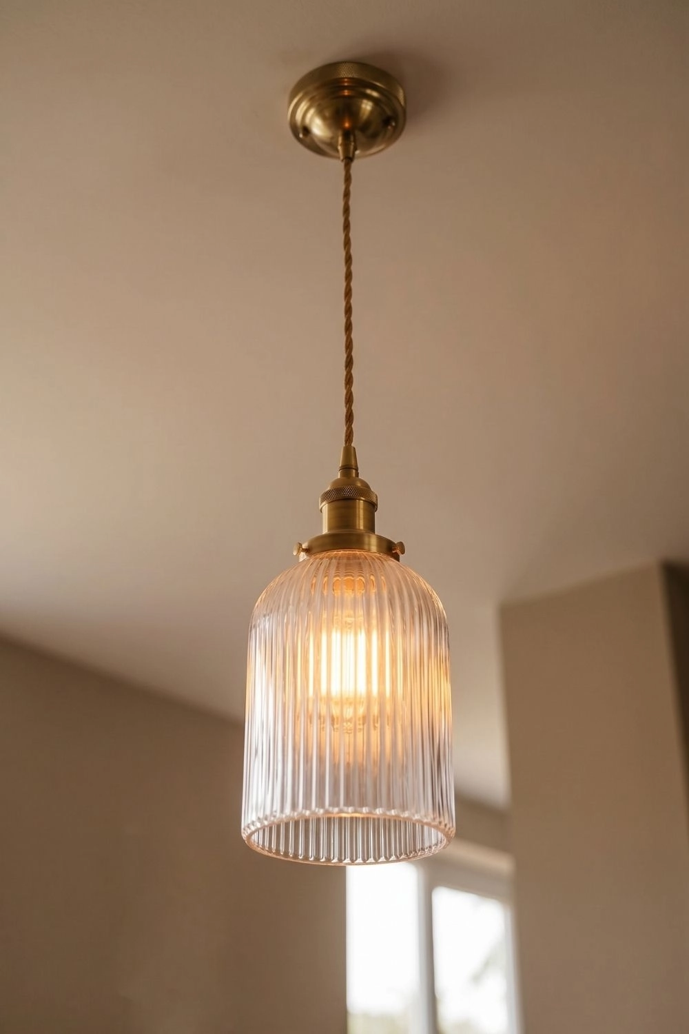 6 Neo Deco Accents Bringing Chrome and Geometric Lines Indoors 3 Fluted ribbed glass pendant light with brass hardware over a dining table