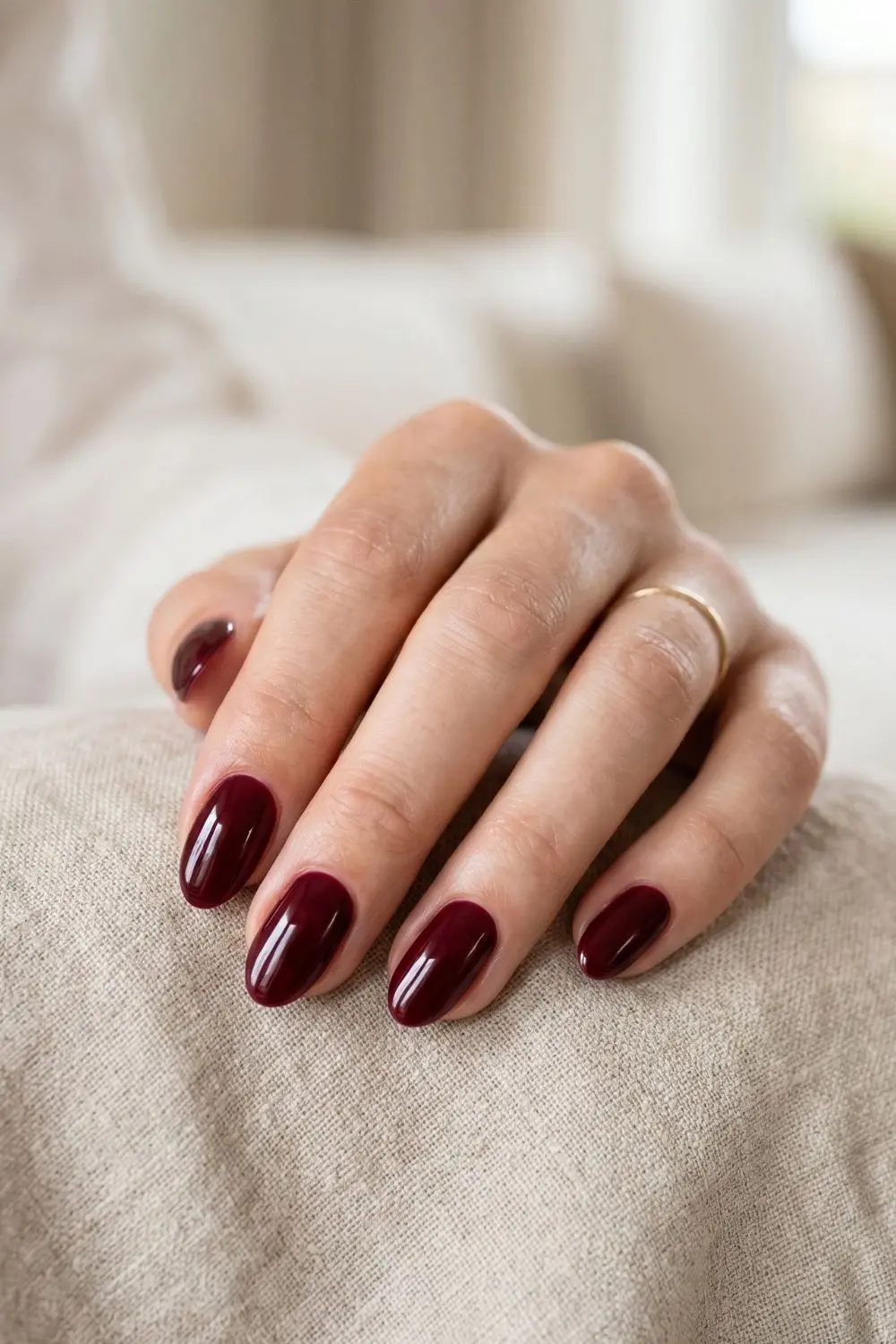 Why Women Are Filing Down Their Long Tips for This Nail Shape 3 Short almond-shaped nails with deep burgundy polish, clean background