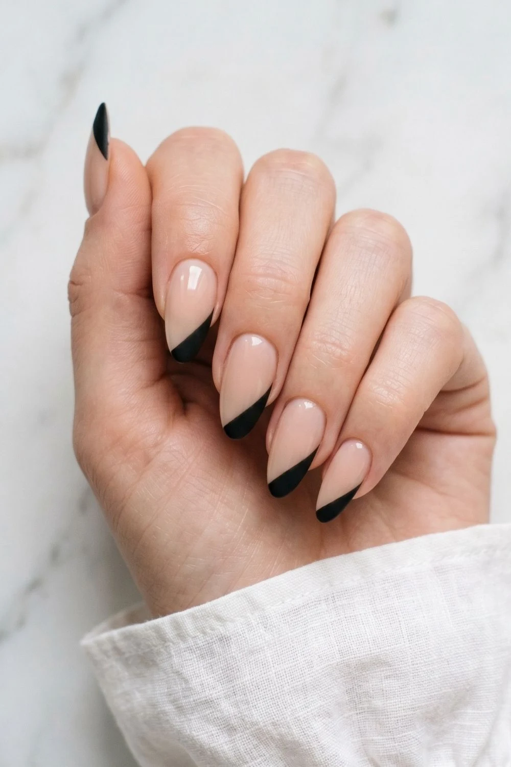 6 Modern French Tip Nail Variations Everyone Is Asking for Right Now 5 Close-up of almond nails with a straight diagonal matte black geometric French tip line on a bare nail base