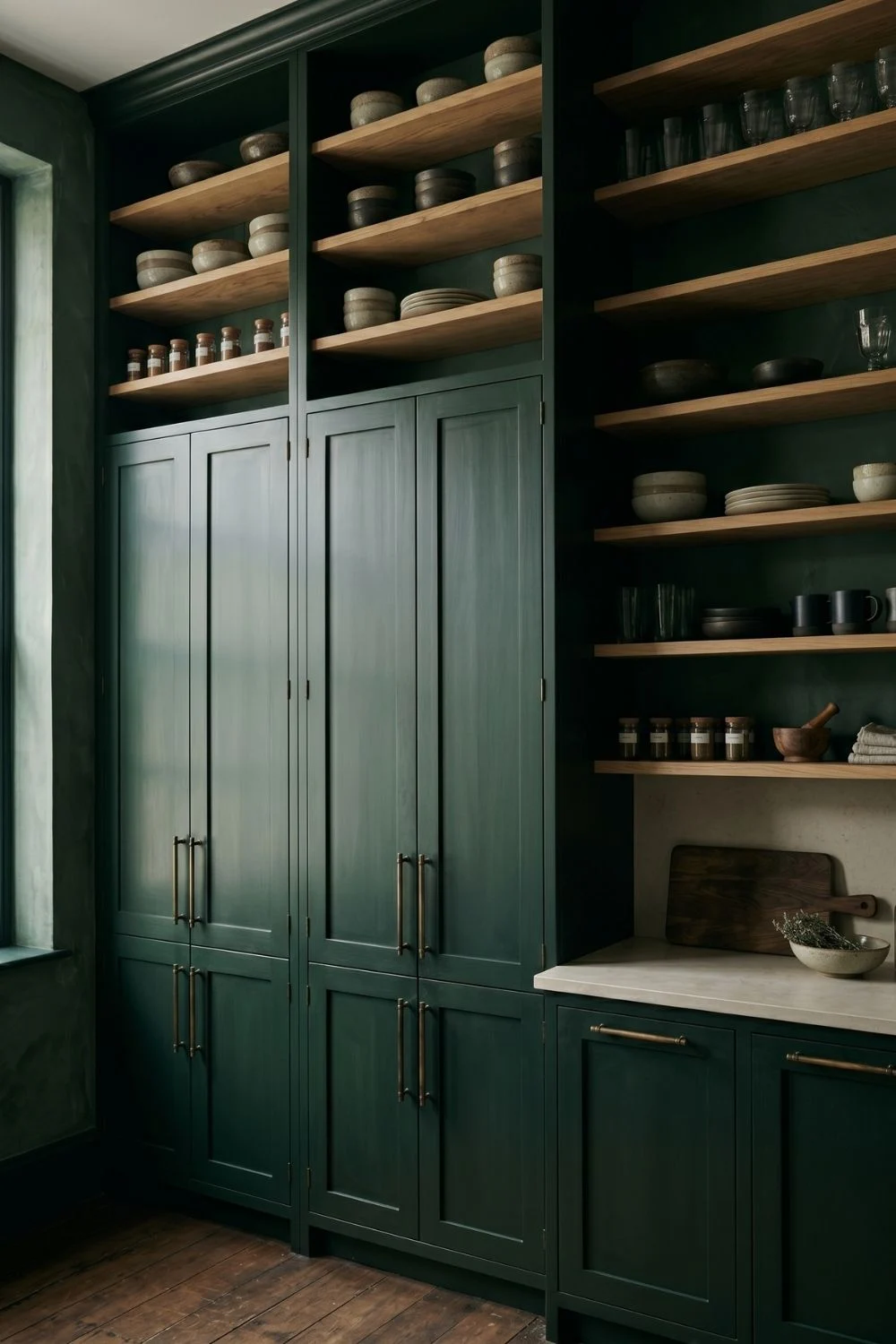 full-height deep forest green kitchen cabinets with aged bronze hardware and raw oak open shelving above