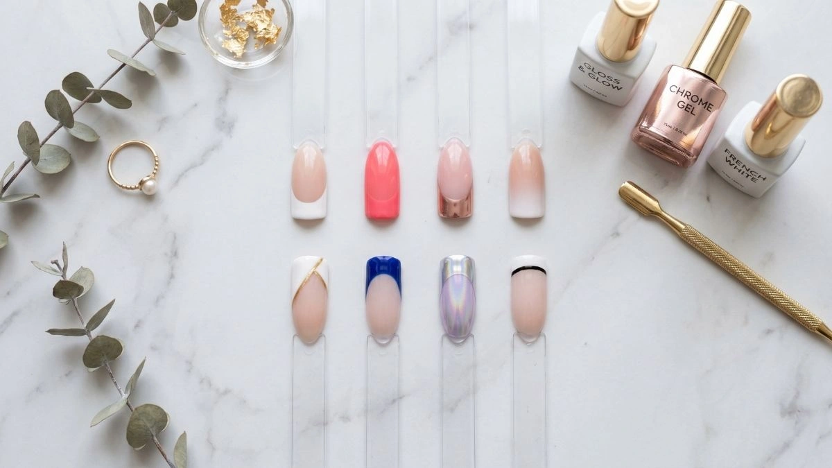 Flatlay of nail swatches showing eight modern French tip variations including color, chrome, geometric, and ombre styles on a marble surface