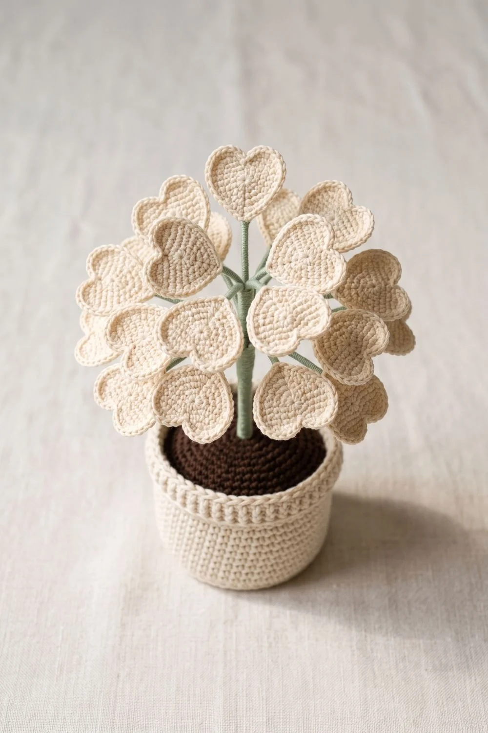 5 Crochet Plant Styles Dominating Pinterest Right Now 5 Crochet heart leaf plant with warm ivory heart-shaped leaves on sage stems in a cream ribbed pot on a neutral textile background